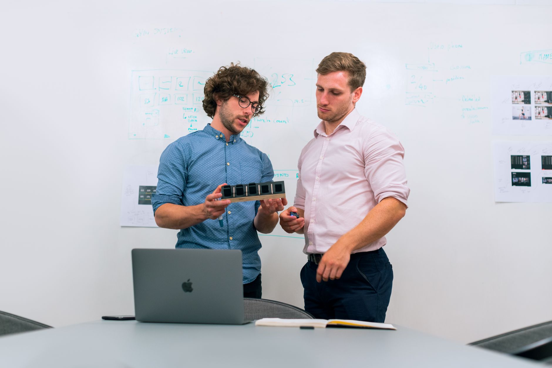 Engineers reviewing a system model and a printed requirements set at a work table